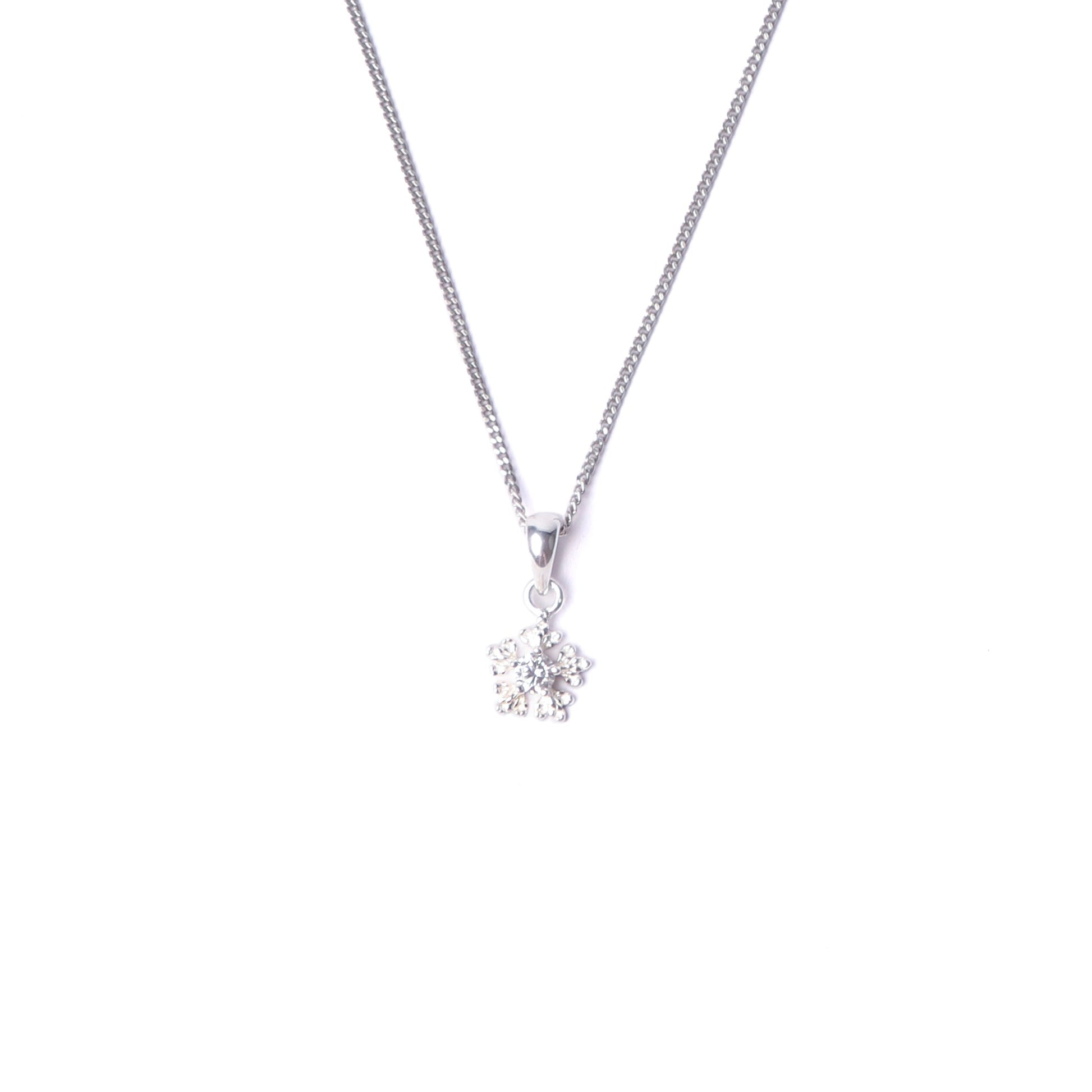 Women's sterling silver snowflake pendant necklace with small cubic zirconia gemstones on the pendant, hanging from a silver chain all set on a white background.