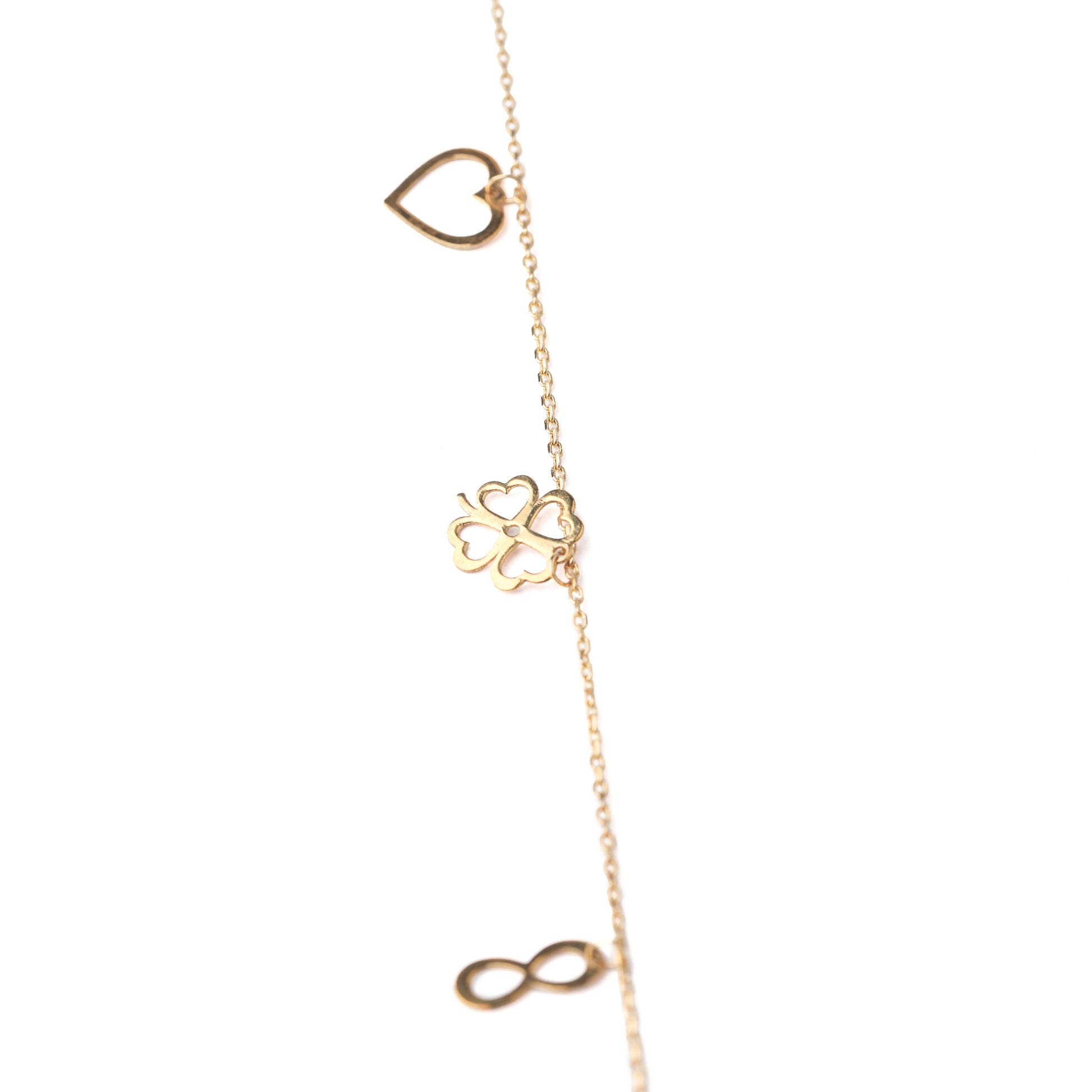 Women's solid gold lucky charm bracelet with heart, four-leaf clover and infinity symbols on a white background