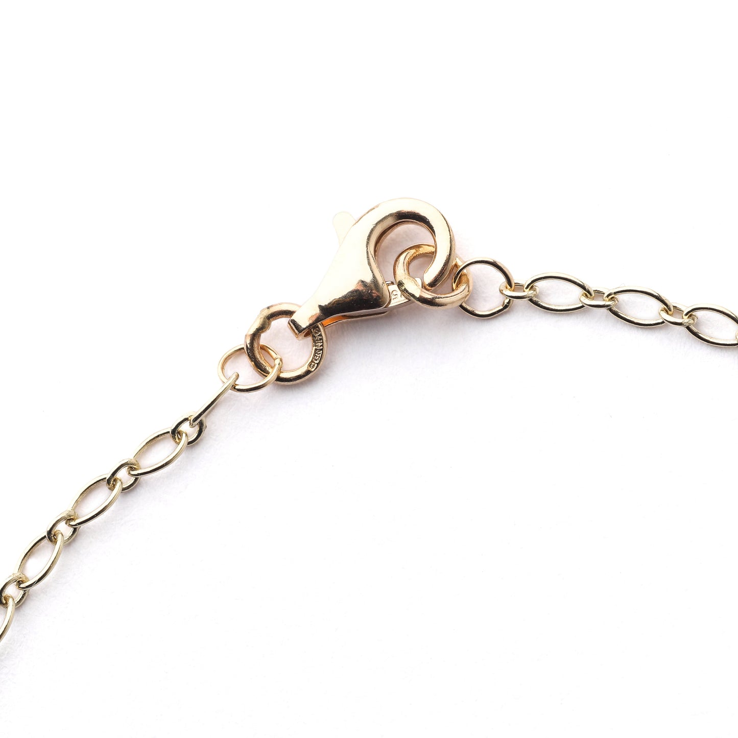 Part of a women's 9K solid yellow gold 2mm oval trace chain bracelet or necklace with clasp on a white background