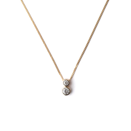 Women's delicate 9K solid yellow gold necklace with a two stone bezel-set cubic zirconia pendant on a white background