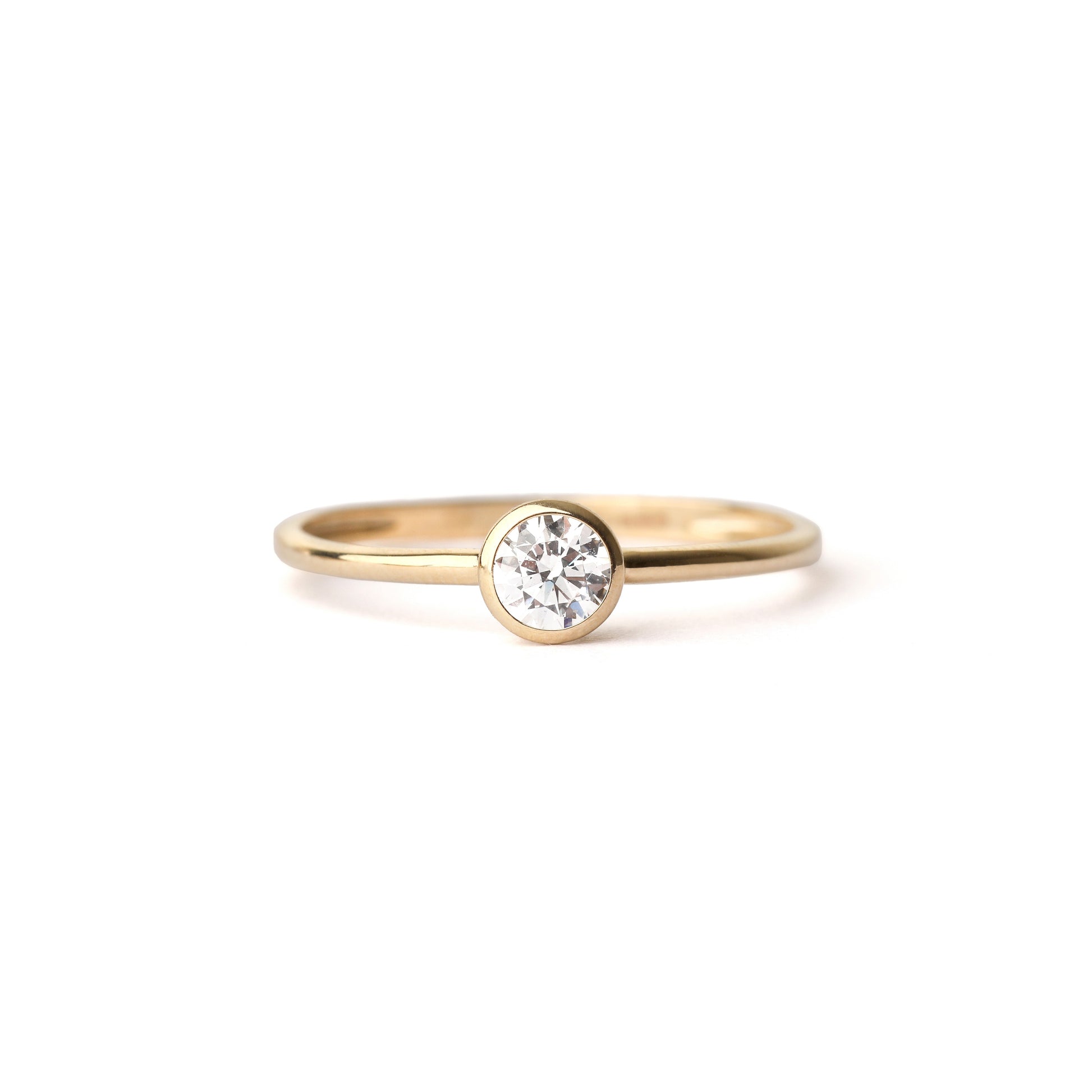 Women's solid yellow gold bezel-set cubic zirconia ring displayed on a white background
