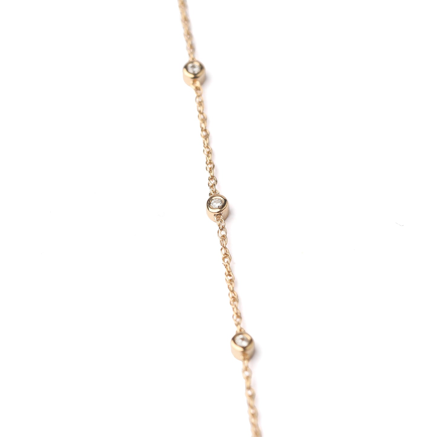 Women's solid gold and delicate three bezel-set diamond bracelet on a white background