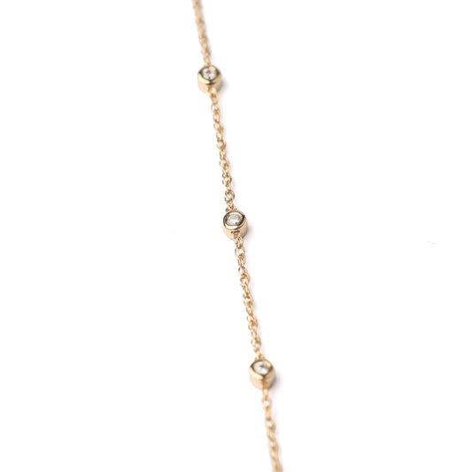 Women's solid gold and delicate three bezel-set diamond bracelet on a white background