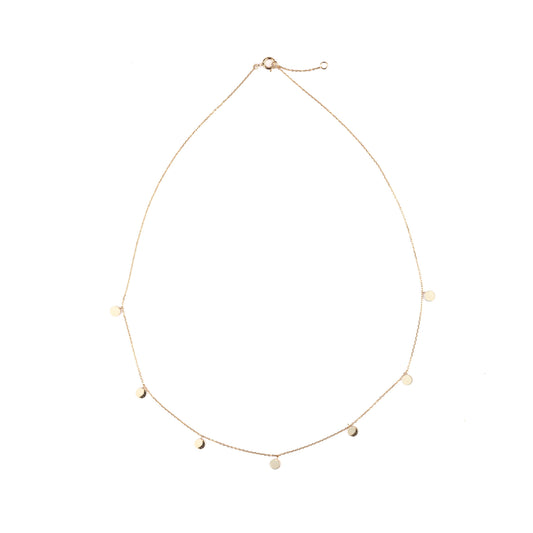 Delicate women's gold necklace with seven small discs on the chain set on a white background