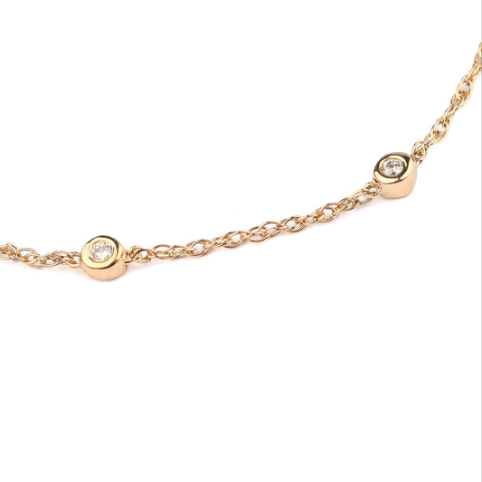 Women's solid gold and bezel-set  diamond bracelet on a white background