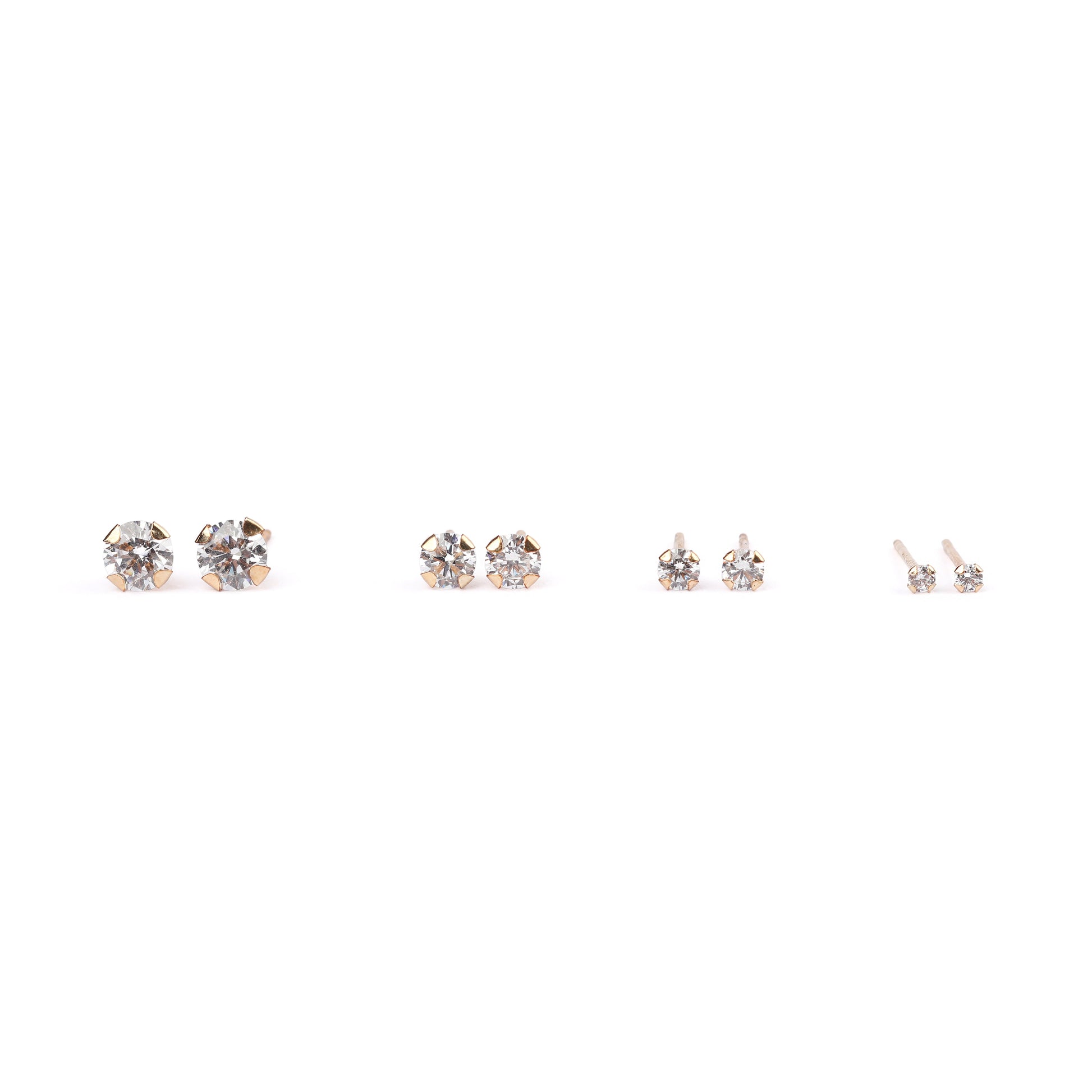 Four pairs of studs of women's classic solid gold and cubic zirconia stud earrings in mini, small, medium and large sizes on a white background