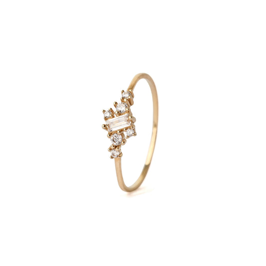 Women's solid yellow gold ring set with six round cut cubic zirconia gemstones equally placed either side of a central baguette shape cubic zirconia. The ring is standing up and is displayed on a white background