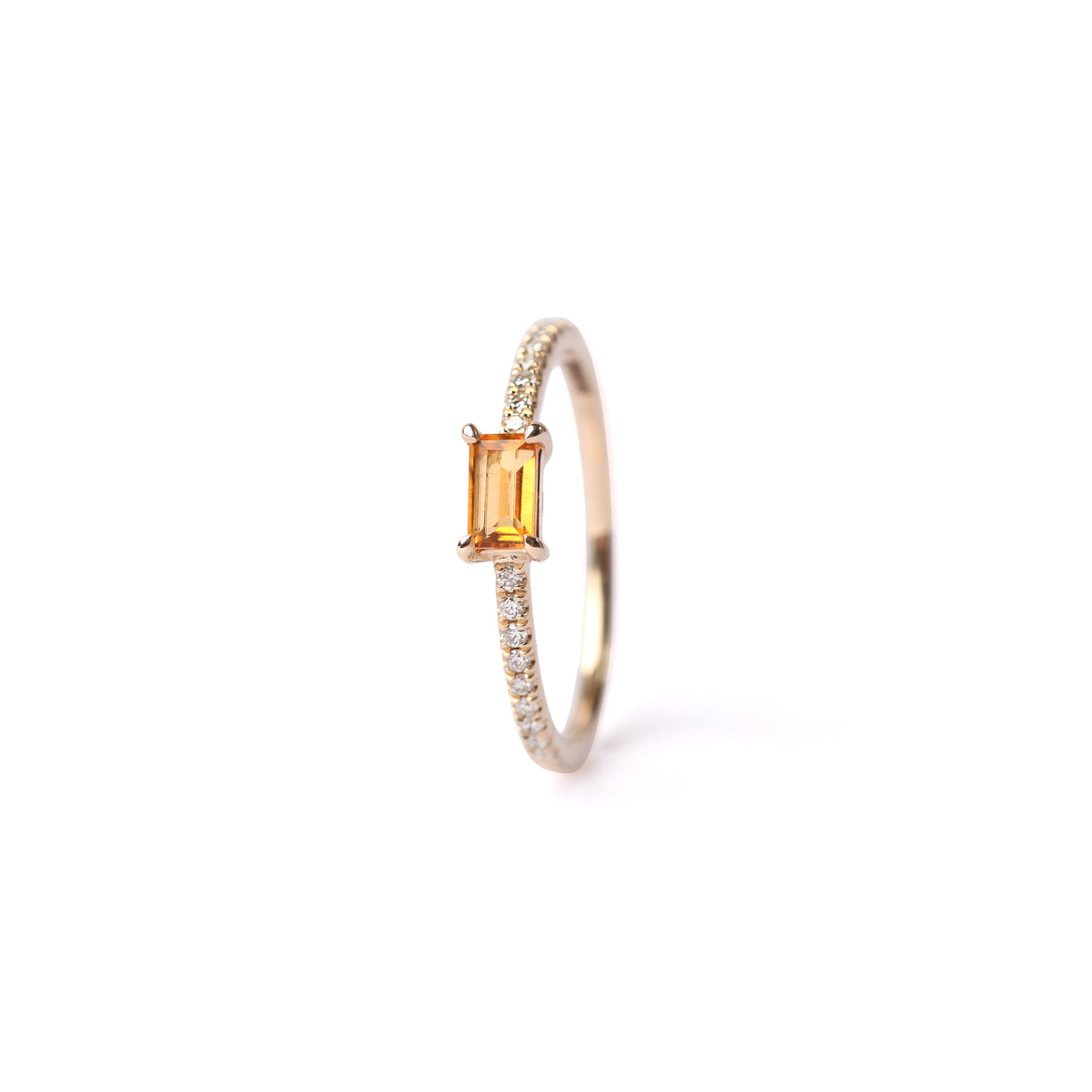 Women's solid yellow gold ring set with a central yellow citrine gemstone and small round diamonds on the shoulders each side of the citrine, displayed on a white background on it's side facing frontwards.