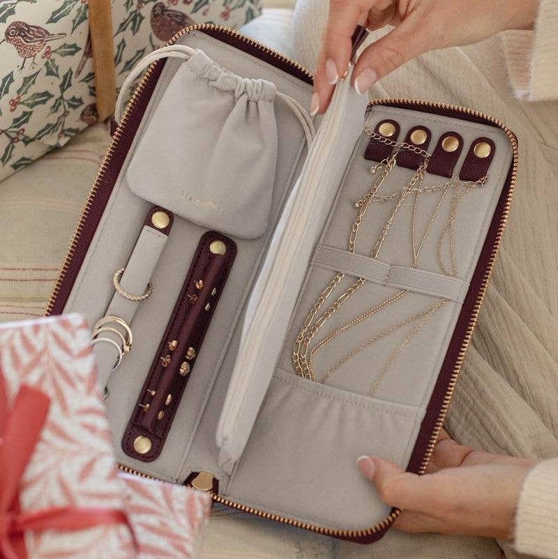 Large burgundy Stackers jewellery roll shown open and held by a hand on a soft surface