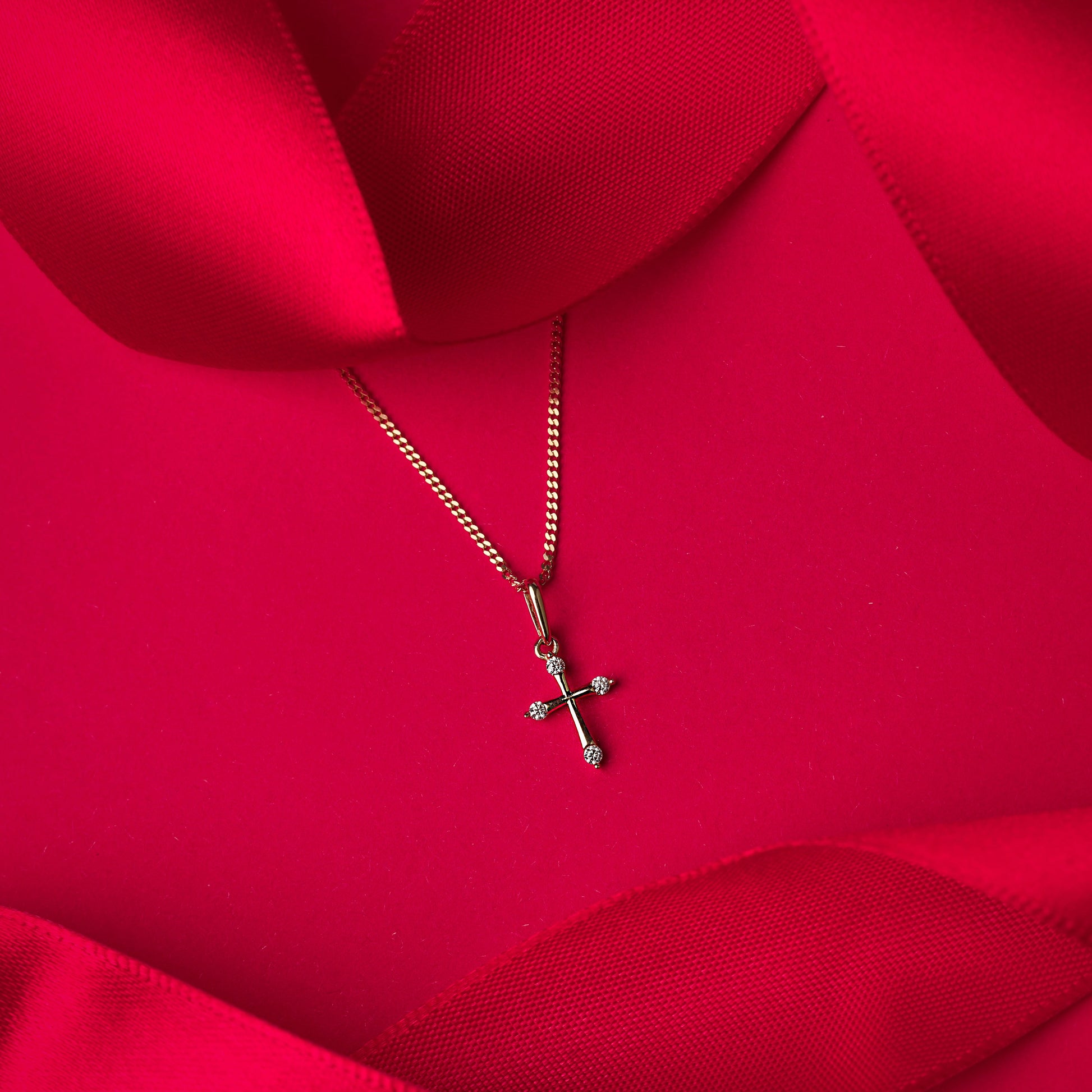 Gold cross pendant on a red fabric background