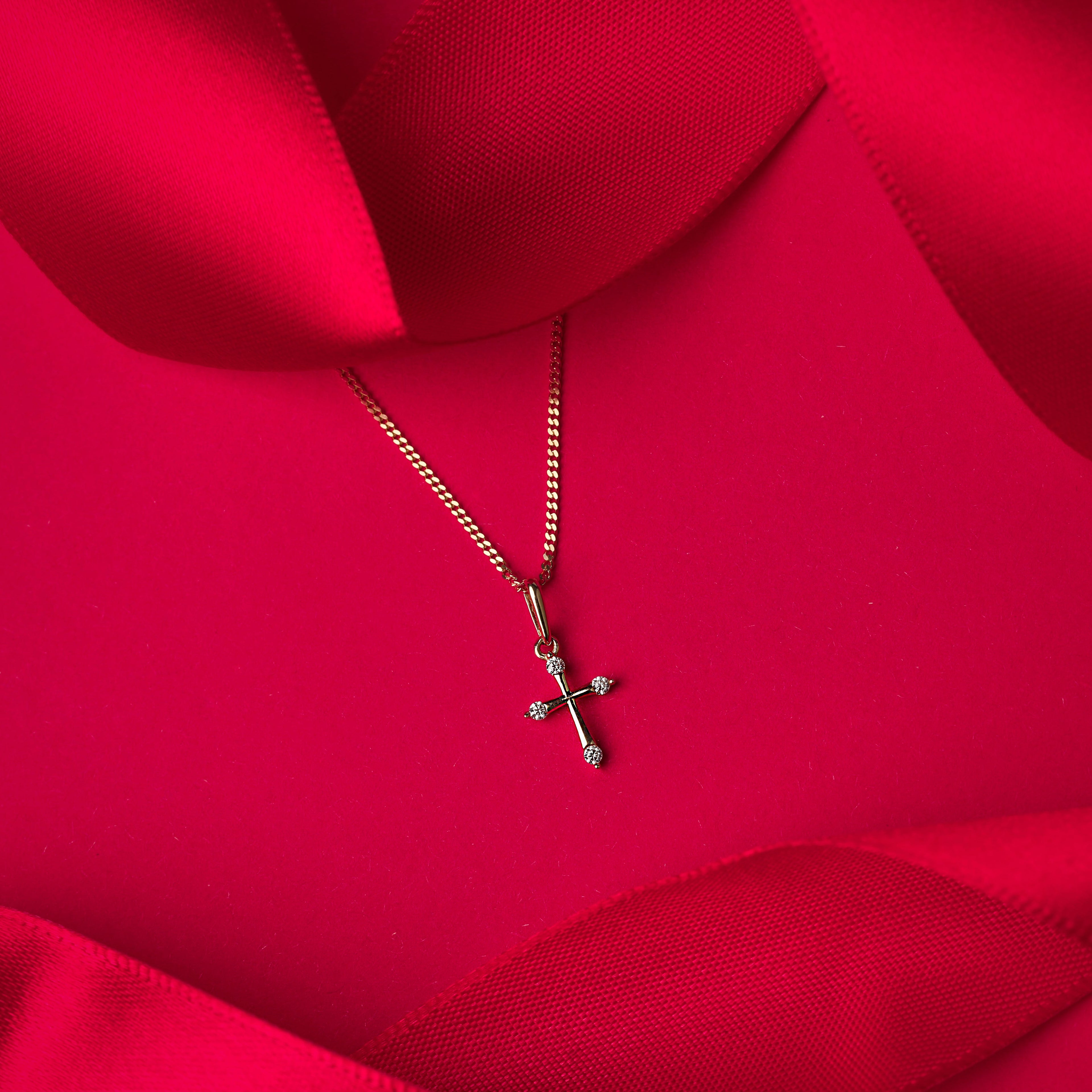 Gold cross pendant on a red fabric background