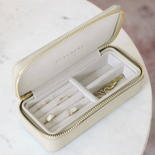 Beige jewelry box with gold jewelry on a marble surface