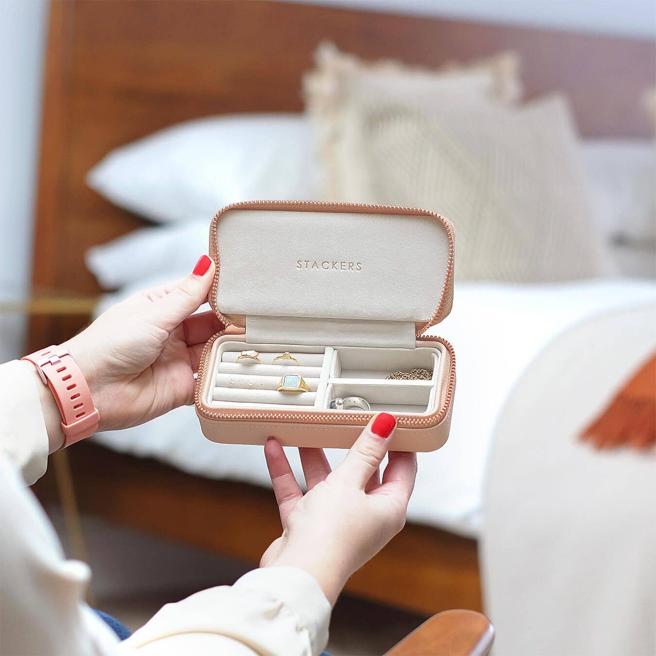 Person holding a Stackers travel jewelry box in medium size blush pink with jewellery inside, blurred background