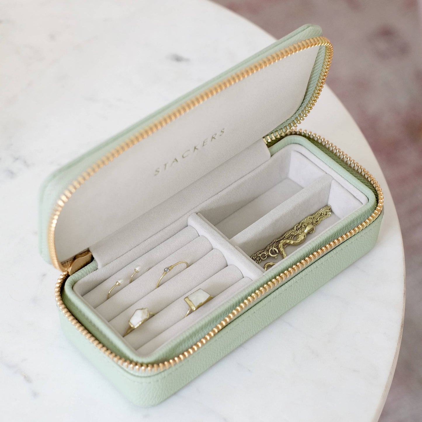 Mint green jewelry box with gold accents on a marble surface