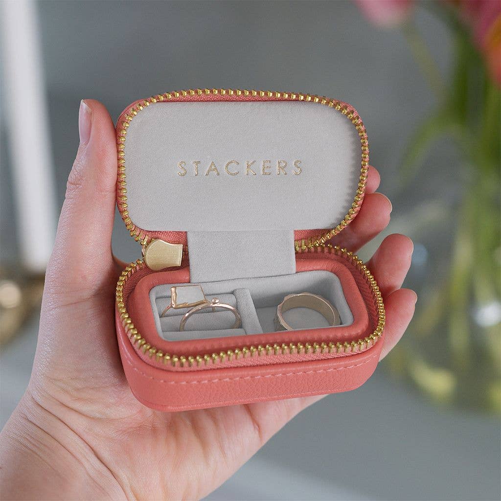 Grapefruit peach mini Stackers travel jewellery case held in a hand with a blurred background