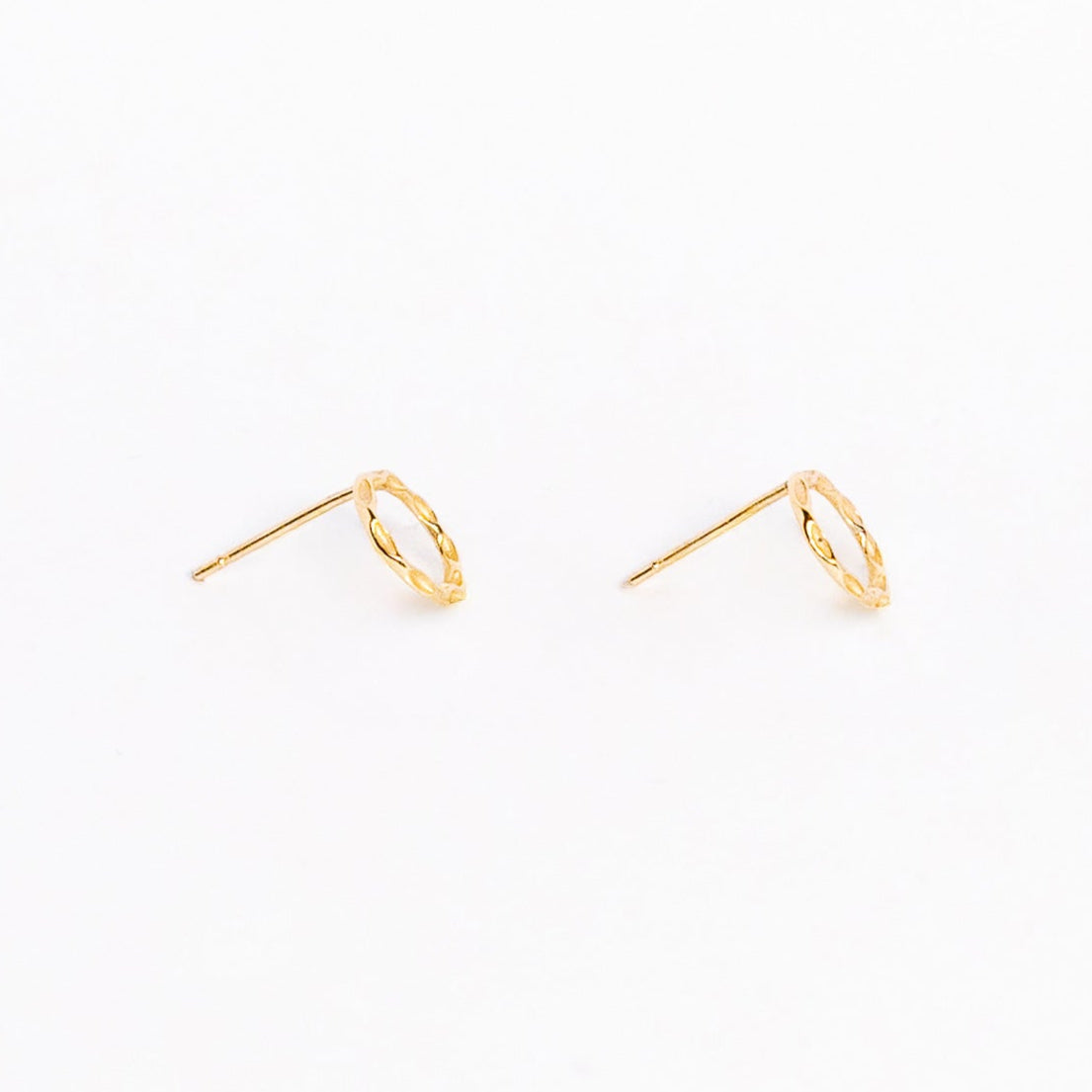 A pair of solid yellow gold circle stud earrings. Both earrings are facing sideways and are set on a white background for the shopper to view.