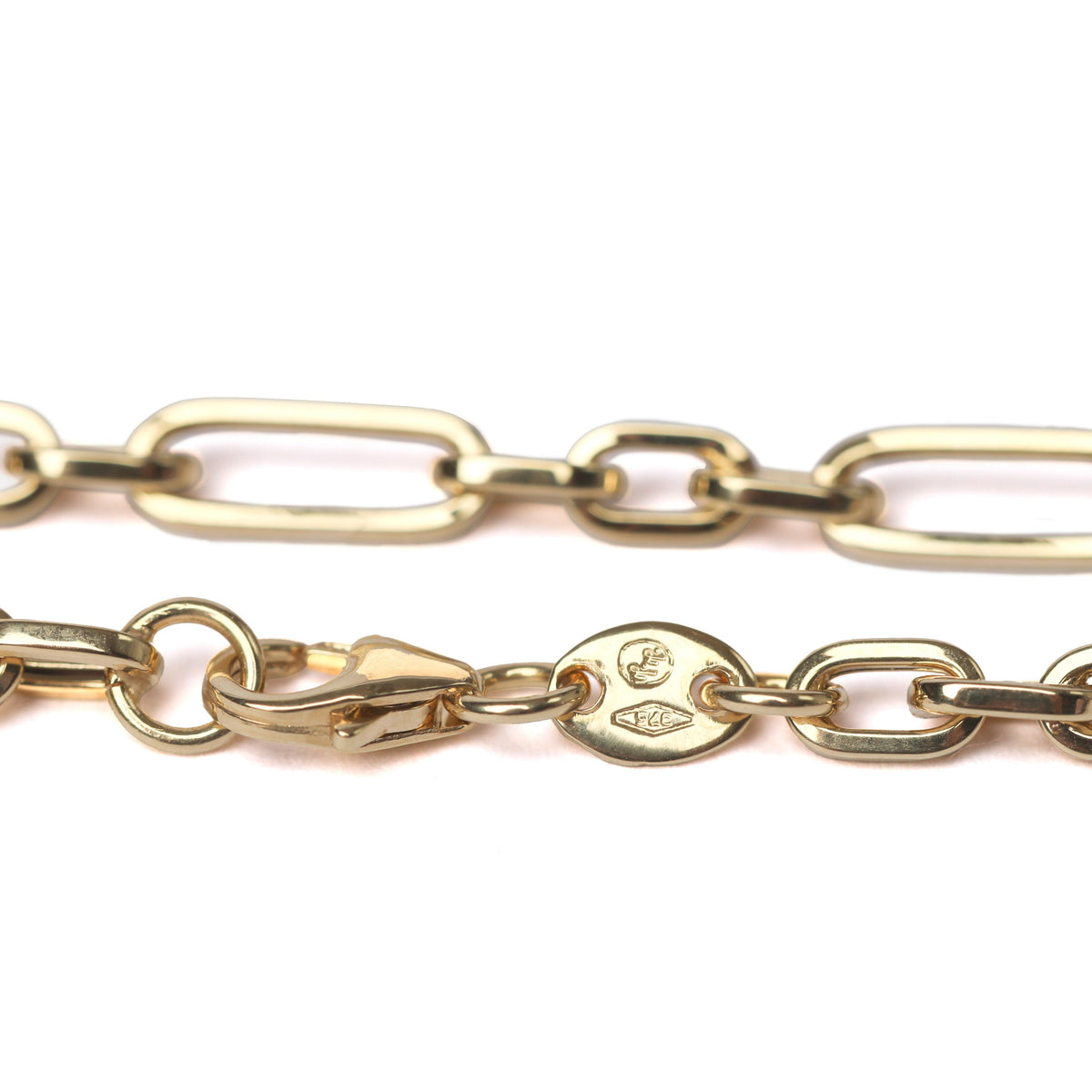 A close-up of a women's gold chain necklace featuring elongated oval links and a lobster clasp with a circular brand tag, set against a plain white background.