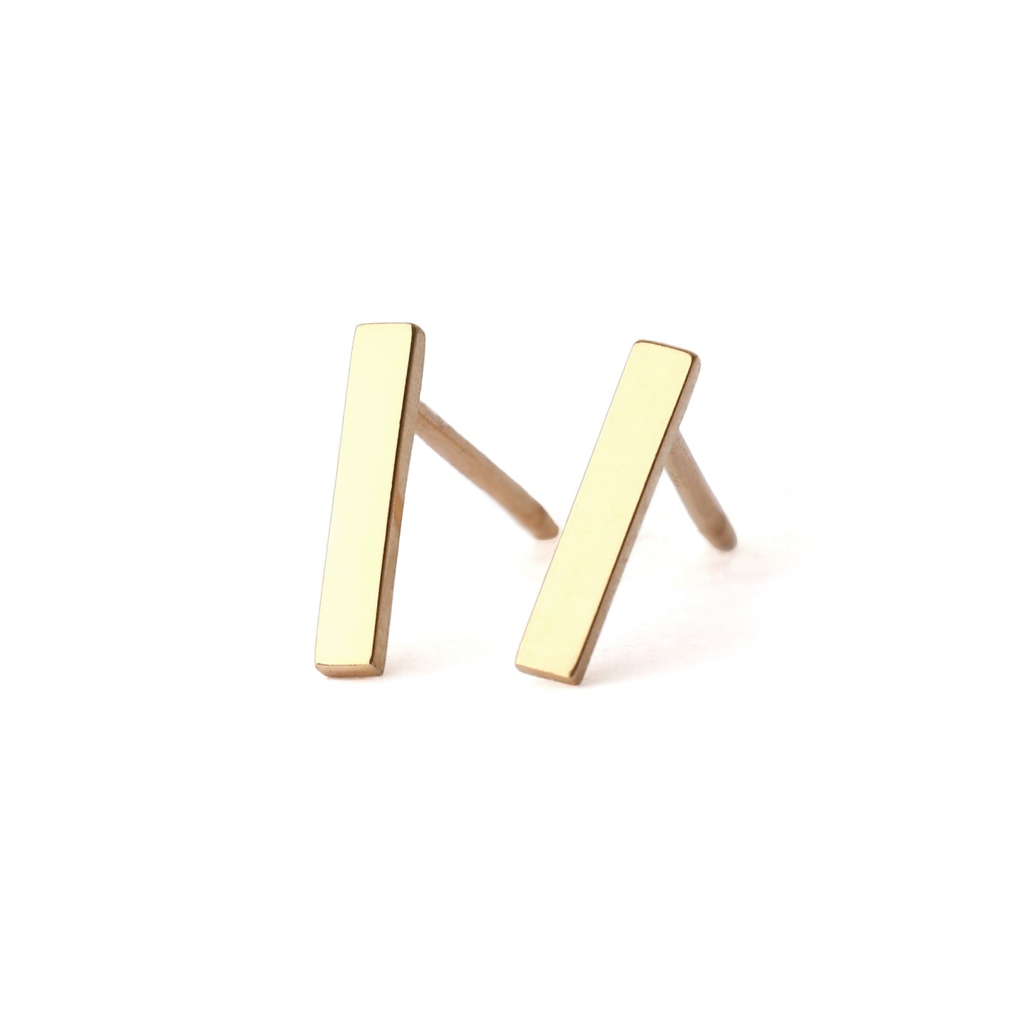 A pair of solid yellow gold bar stud earrings set on a white background for the shopper to view, both facing forwards.