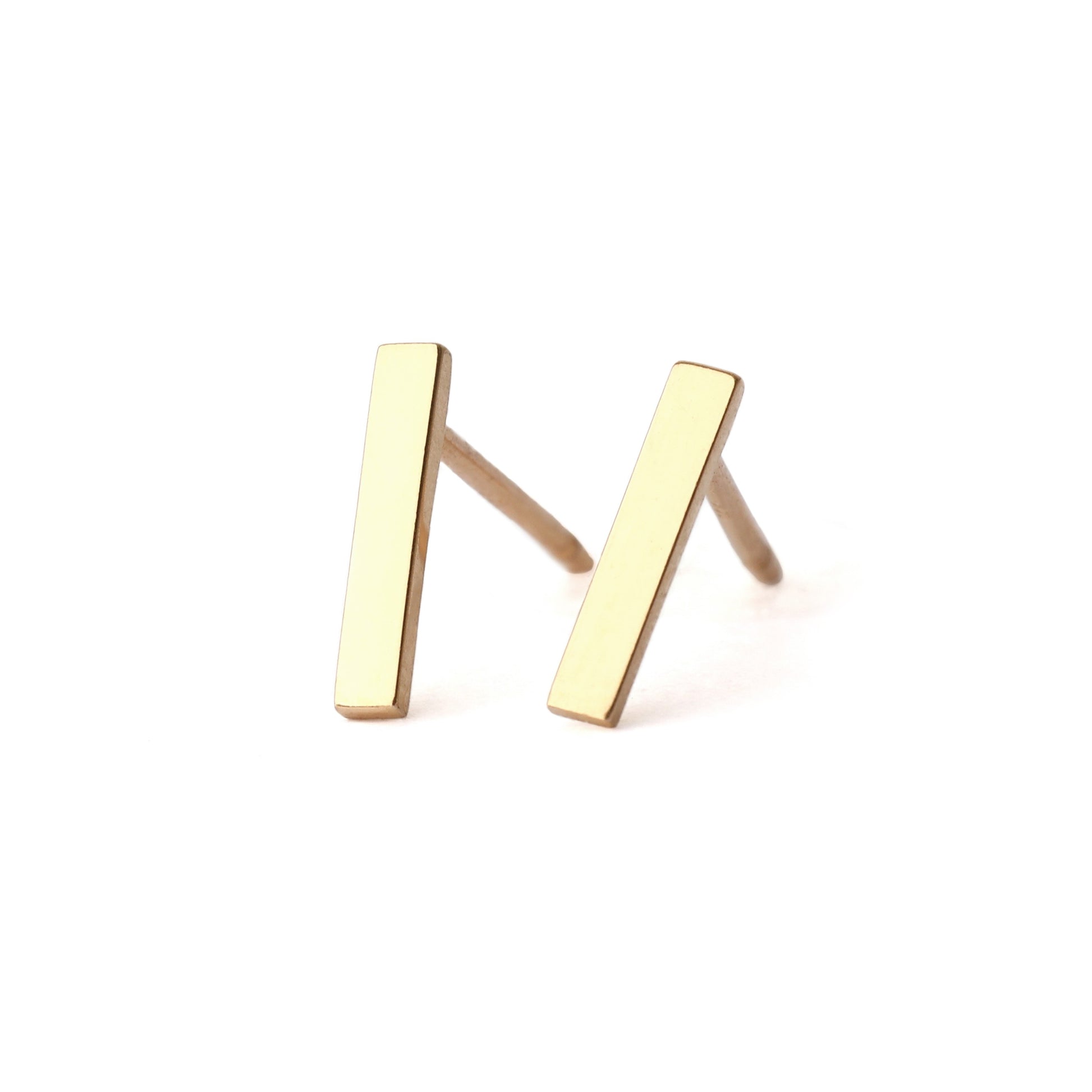 A pair of solid yellow gold bar stud earrings set on a white background for the shopper to view, both facing forwards.