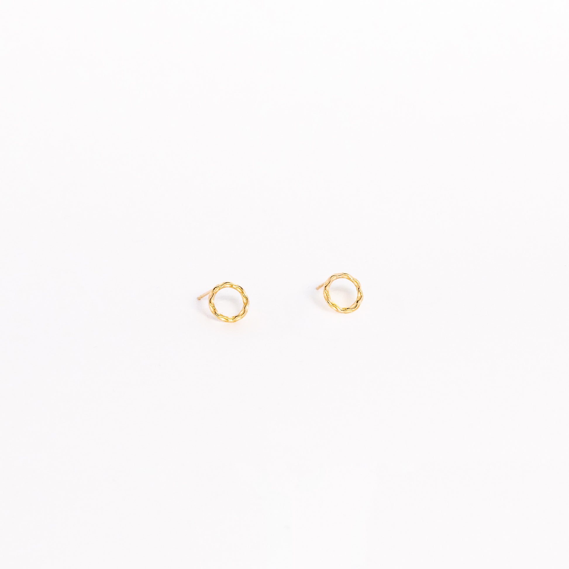 A pair of solid yellow gold circle stud earrings. Both earrings are facing forward and are set on a white background for the shopper to view.