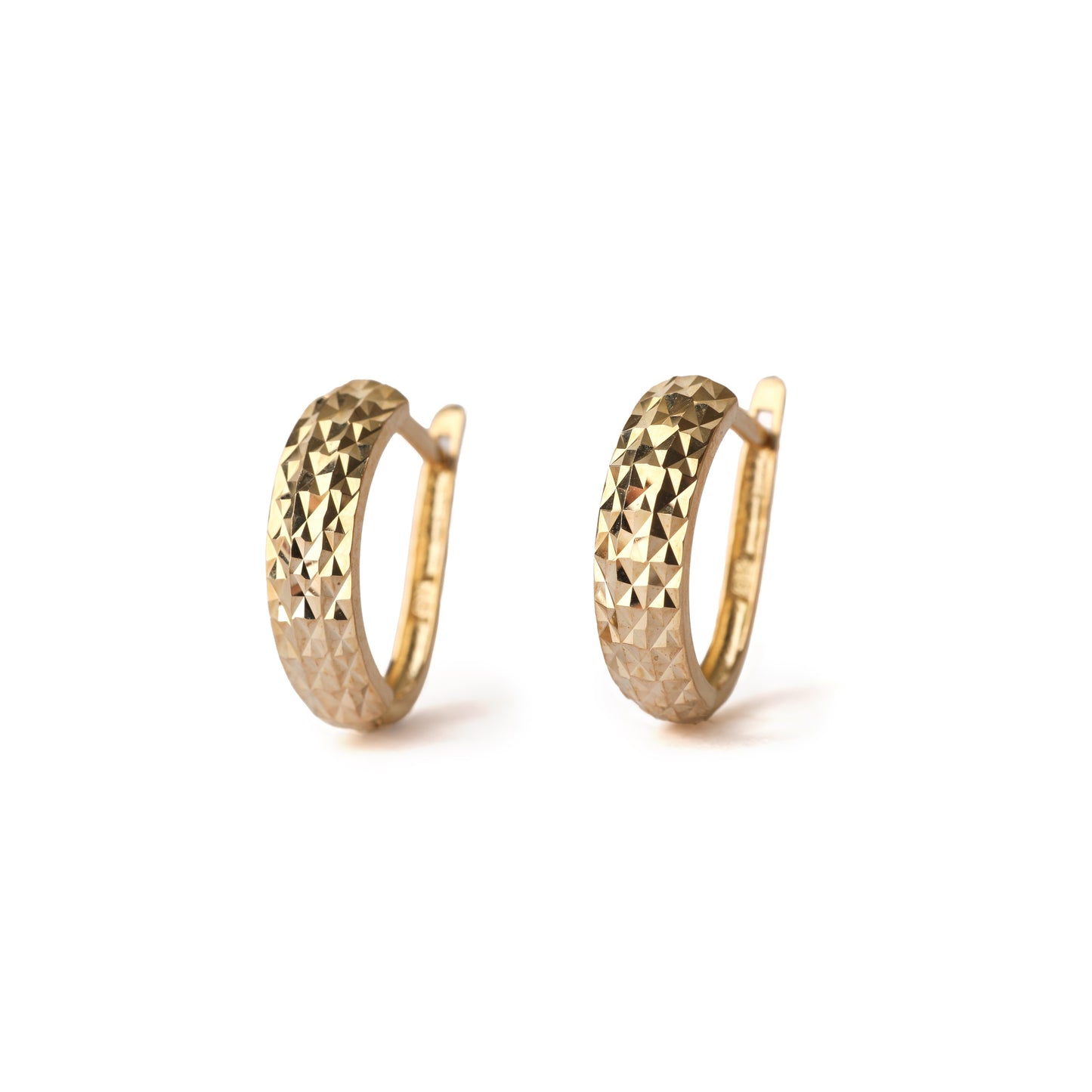 A pair of solid yellow gold huggie hoop earrings with a diamond cut design on the front. Both face straight on and are set on white background for the shopper to view.