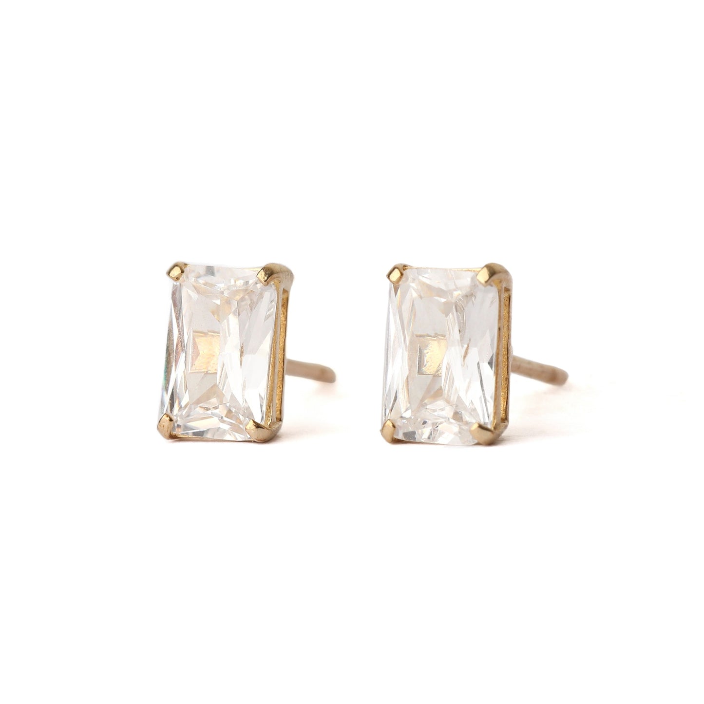 A pair of solid yellow gold and emerald cut cubic zirconia stud earrings. Both face face forward and are displayed on a white background.