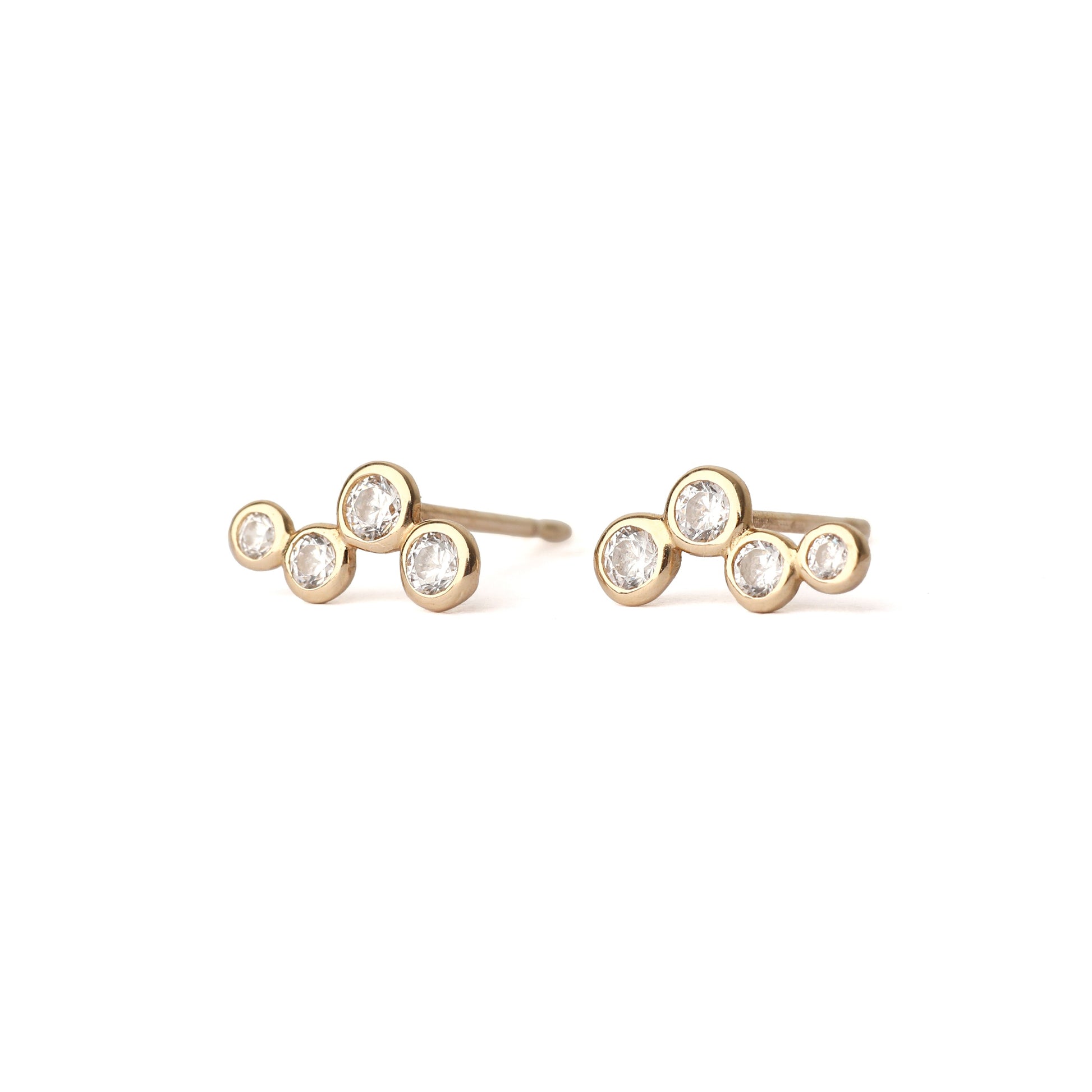 A pair of solid yellow gold bezel-set cubic zirconia earrings. Each earring has four cubic zirconia gemstones of various sizes. Both face forwards and  are set on a white background for the shopper to view.
