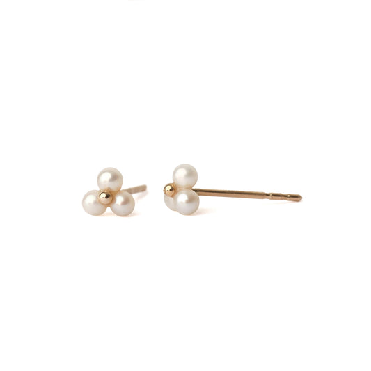 A pair of solid yellow gold freshwater pearl stud earrings. Each earring has three tiny pearls surrounding a small gold centre like a flower. The earrings are displayed on a white background for the shopper to view, with one straight on and one side on.