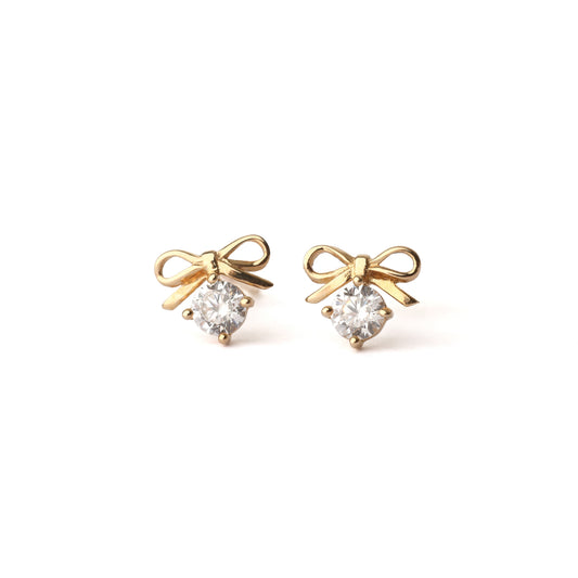 A pair of solid yellow gold bow earrings with a moissanite gemstone under the bow. Both earrings face forwards and are set on a white background for the shopper to view.