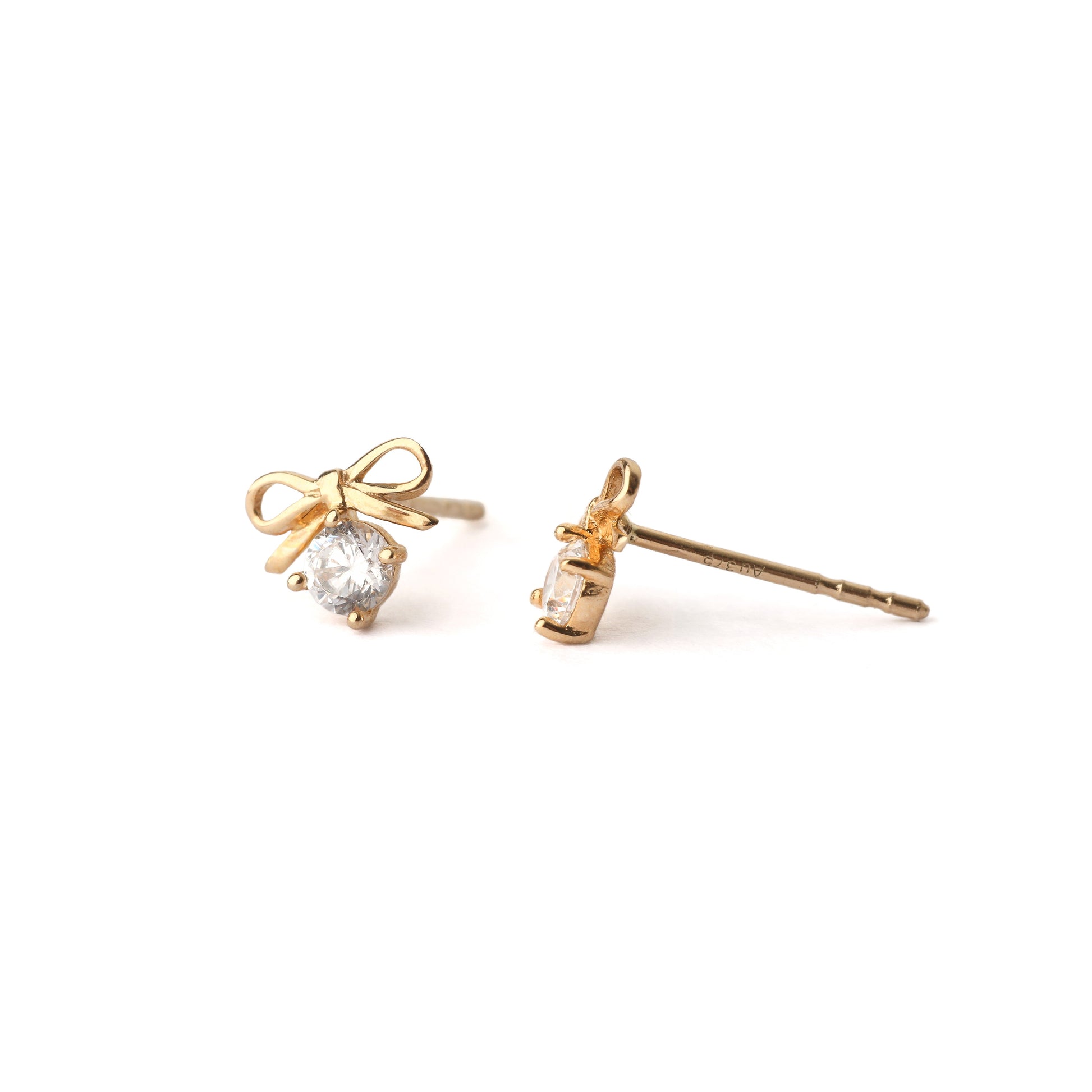 A pair of solid yellow gold bow earrings with a moissanite gemstone under the bow. One earring faces forwards the other is side on and both are set on a white background for the shopper to view.