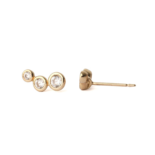 A pair of women's solid gold earrings, each with three cubic zirconia gemstones in a bezel setting. The earrings are on a white background, with one earring facing forward and one side on for the shopper to see.