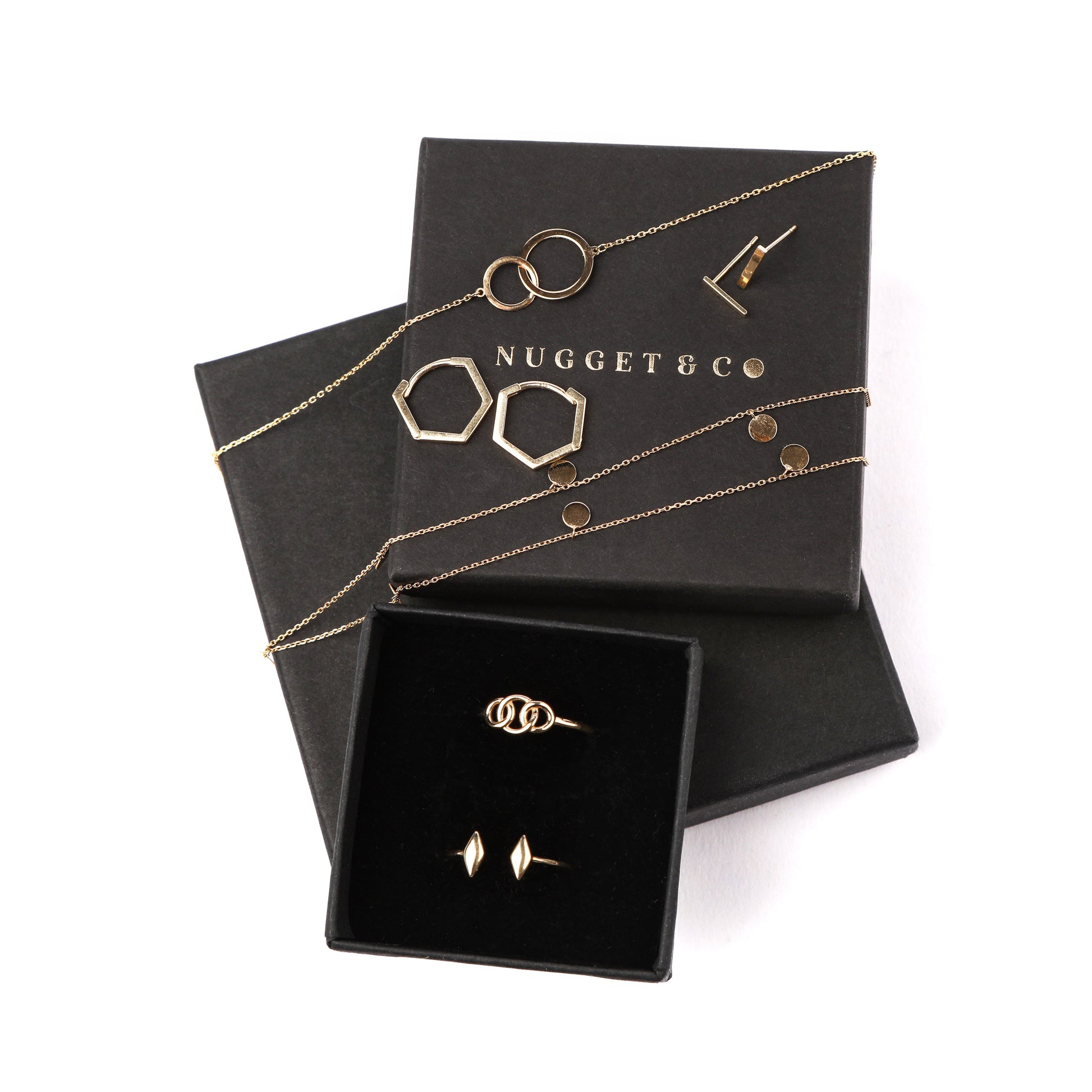 Women's solid gold geometric style jewellery set on a 'Nugget & Co' branded jewellery box on a white background