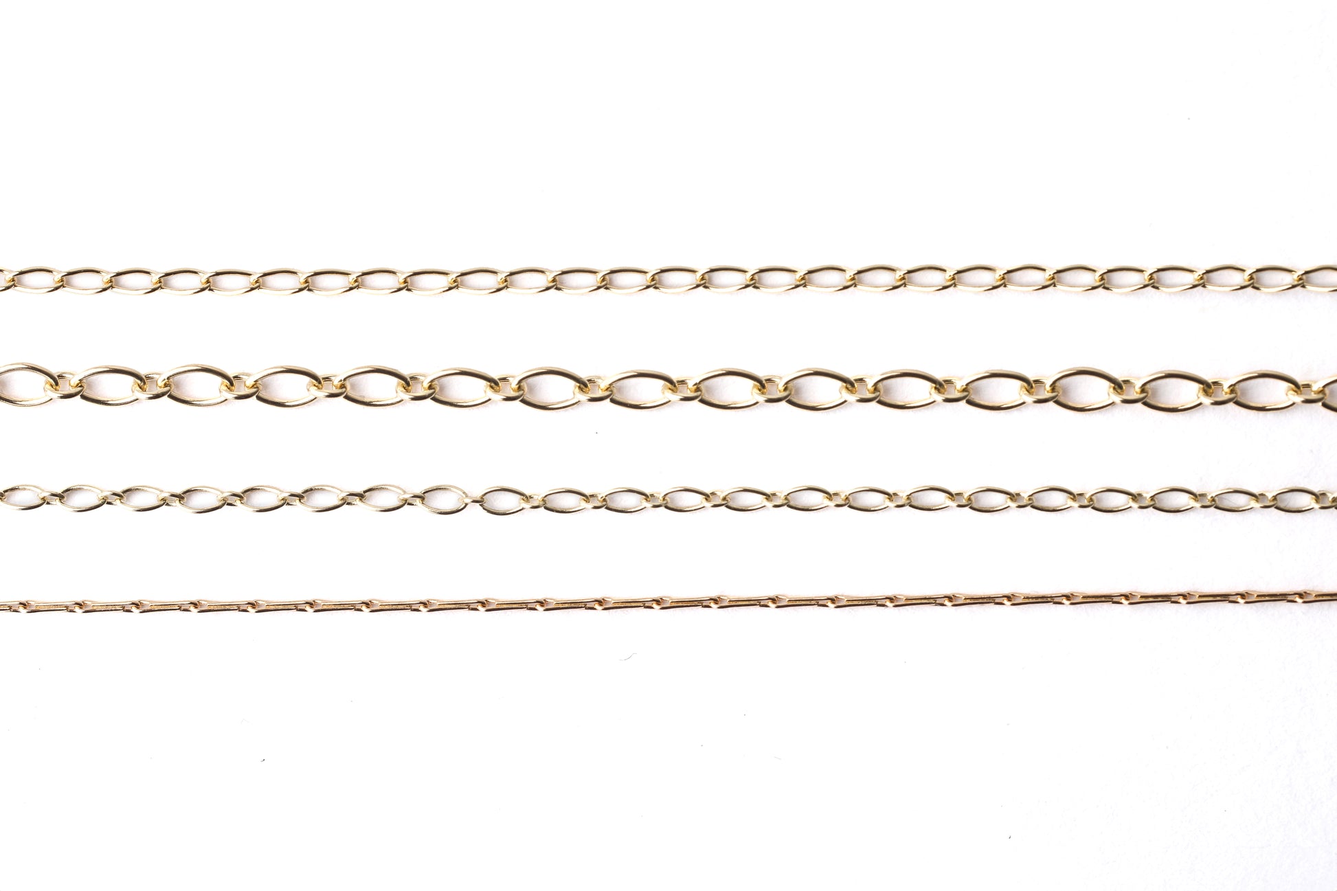 Four different women's solid gold chains, hayseed, trace, oval trace 2mm and oval trace 3.5mm for necklace and bracelets on a white background