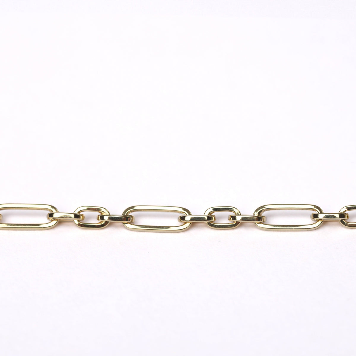 A close-up of a women's solid gold paperclip chain link bracelet laid horizontally against a plain white background.